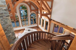 A spacious interior with a wooden staircase, stone wall, and large windows offering views of the outdoors. - Private Luxury 4 Bedroom Estate on 4 Acres with over 1,100 feet of shoreline! (Orcas)