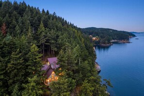 A secluded cabin surrounded by dense forest, overlooking a calm body of water. - Private Luxury 4 Bedroom Estate on 4 Acres with over 1,100 feet of shoreline! (Orcas)
