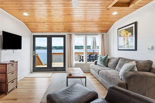 Una sala de estar con techo de madera, un sofá, un televisor y vistas al exterior.