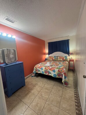 Ein Schlafzimmer mit Bett, Kommode und einem beleuchteten Spiegel.