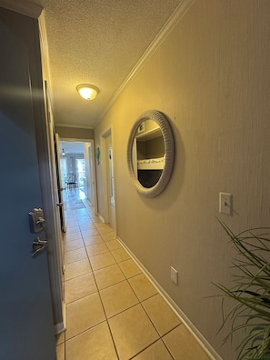 A hallway with a door on the left, a wall-mounted mirror, and a tiled floor. - Cozy 1-bedroom condo in peaceful Hilton Head Island with private beach access (Hilton Head Island)