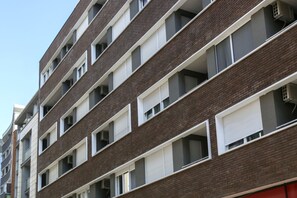 Ein mehrgeschossiges Wohngebäude mit Backsteinfassade, weißen Fensterrahmen und Balkonen.
