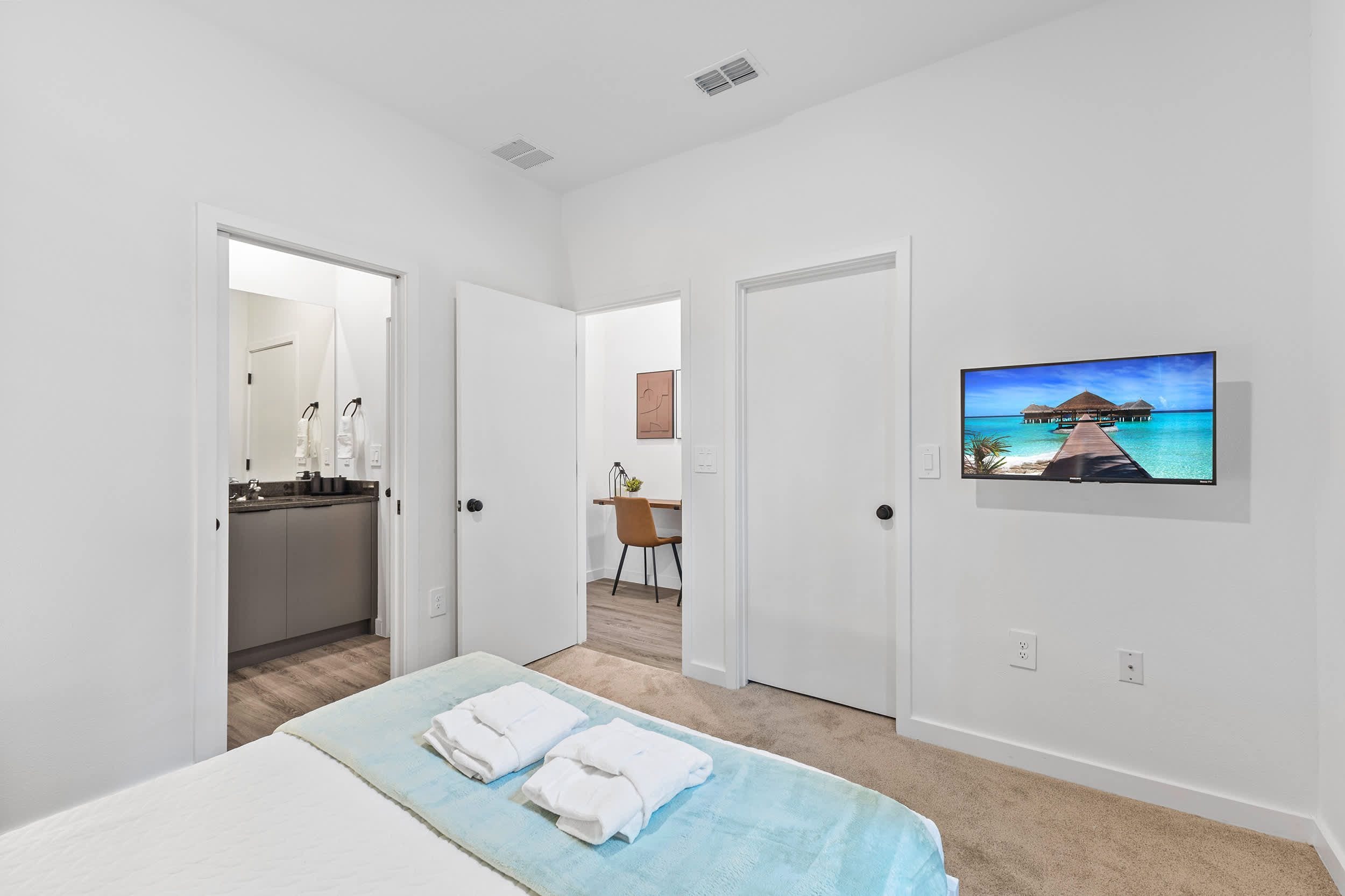 A hotel room with a bed, a desk, a chair, a television, and a bathroom.