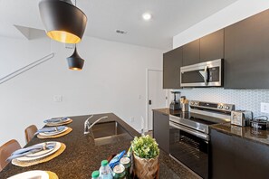 Een moderne keuken met een centraal eiland, roestvrijstalen apparatuur en een hanglamp.