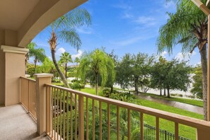A balcony with a view of a landscaped area including trees and a body of water. - Luxury 3BR Modern Design Lake Views Vista Cay (Orlando)