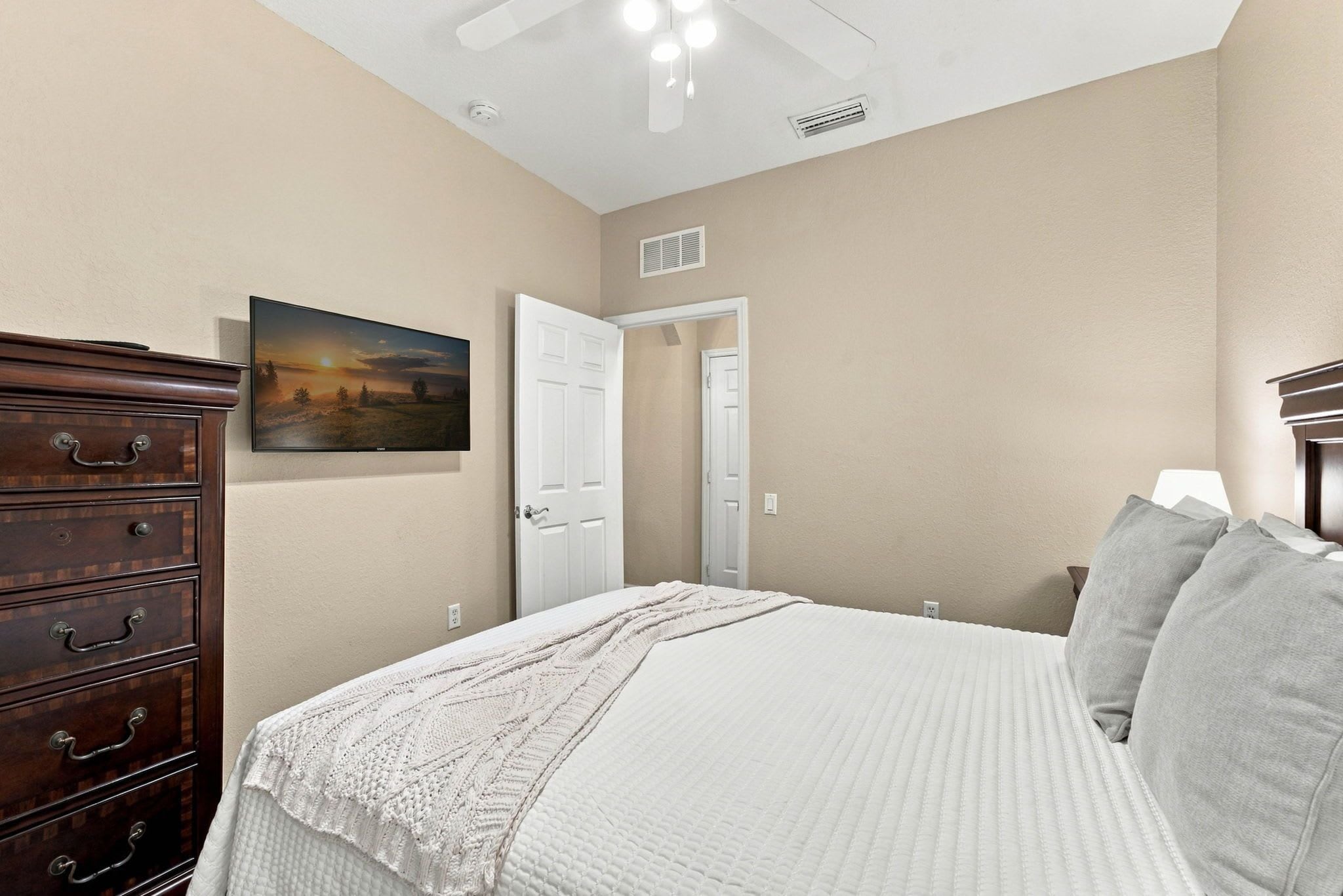 Une chambre à coucher avec un lit, une commode, un tableau et une porte.