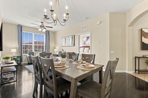 A dining area with a wooden table set for four, surrounded by chairs. - 3BR Vista Cay Conventions Parks and Orlando Fun (Orlando)