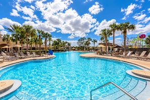 A large outdoor swimming pool with lounge chairs and palm trees. - Chic 6BR Pool Themed Rooms Near Disney (Kissimmee)