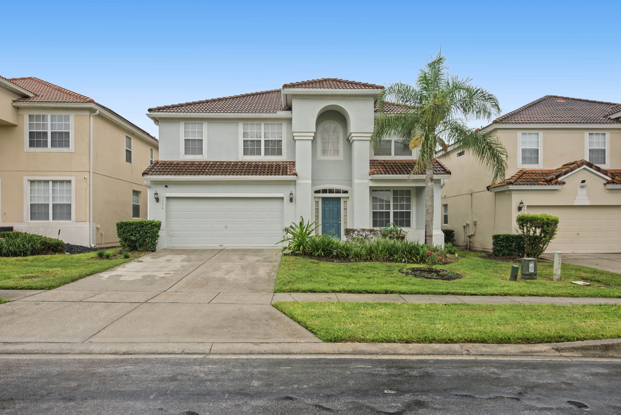 A residential building with a central entrance, a garage, and a well-maintained lawn.