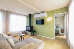 Een moderne woonkamer met een bank, een bijzettafeltje, een televisie en een groene accentmuur.