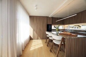 Een moderne keuken met houten kastjes, een centraal eiland met barkrukken en uitzicht op de stad.