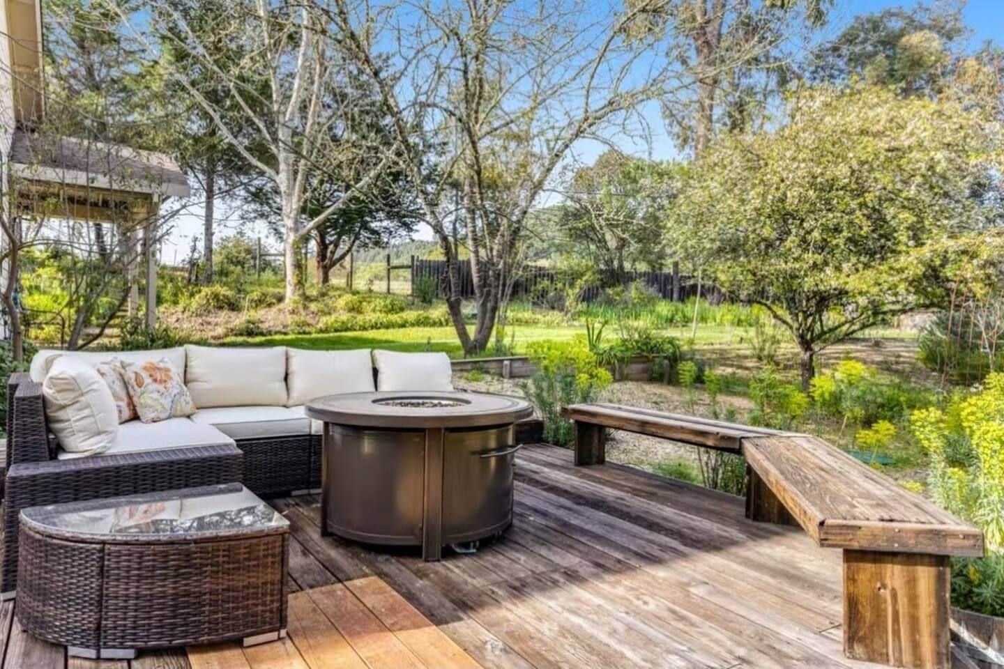 An outdoor patio with a wicker sofa, a round table, and a bench.