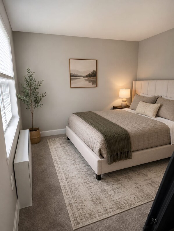 Une chambre à coucher avec un lit, une table de chevet, une lampe et un tableau accroché au mur.