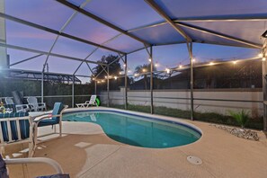 An outdoor swimming pool with lounge chairs and string lights. - Florida Getaway-Pool and Golf Retreat near Disney (Haines City)