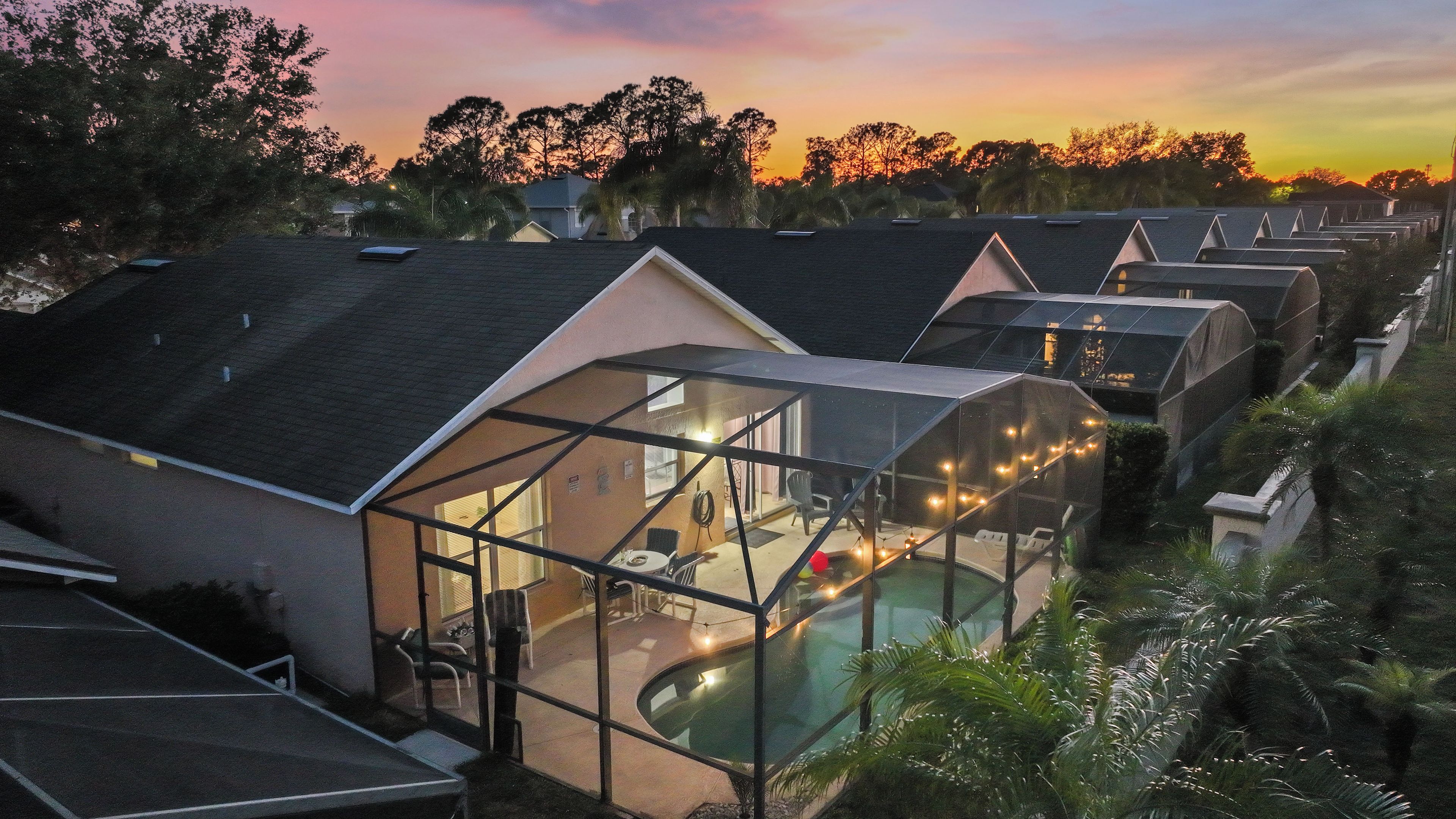 A residential area with multiple houses, each featuring a swimming pool and a glass-enclosed patio area.