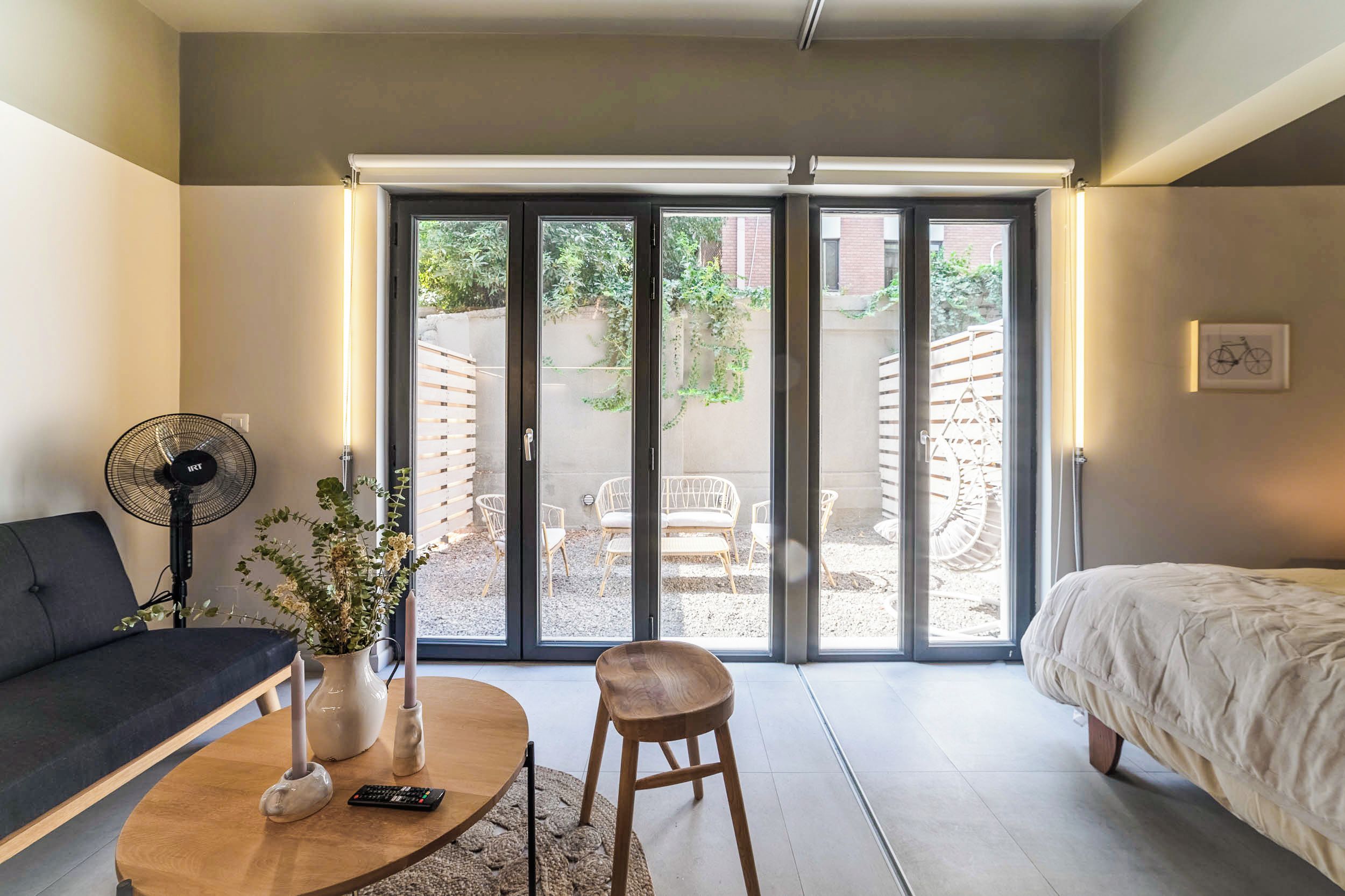 A modern bedroom with a bed, a sofa, a coffee table, and a fan.