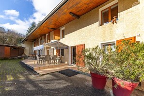 A building with a covered patio, outdoor seating, and potted plants. - The Little Warrior (CHAMBERY)