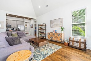 Uma sala de estar moderna com um sofá cinzento, mesa de centro de madeira e um armário com padrão herringbone.