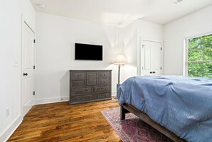A bedroom with a bed, dresser, lamp, and a TV on the wall. - 3 bedroom, 2 bath, with pool house, lake-access, boat slip on Lake Martin (Tallassee)