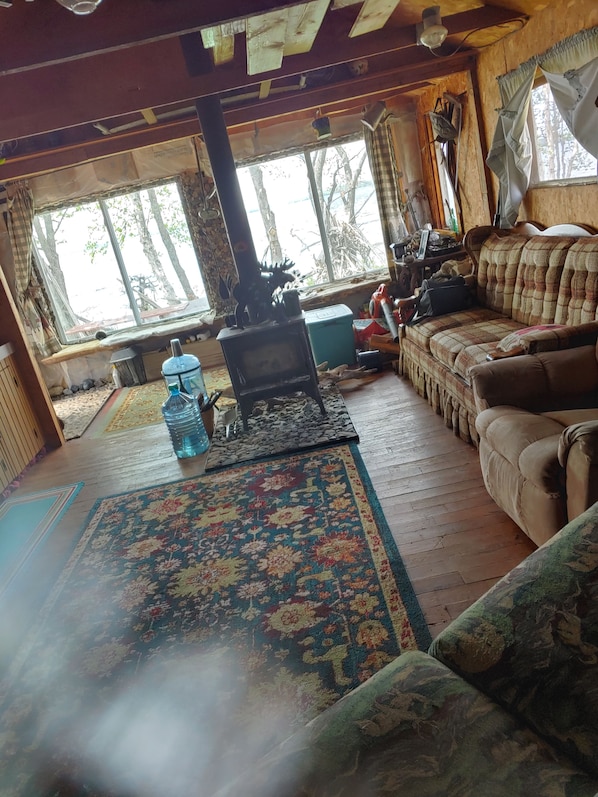 A cozy living room with a fireplace, a sofa, and a large window overlooking trees.