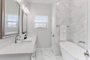 Un bagno con doppio lavandino, vasca da bagno e finestra.