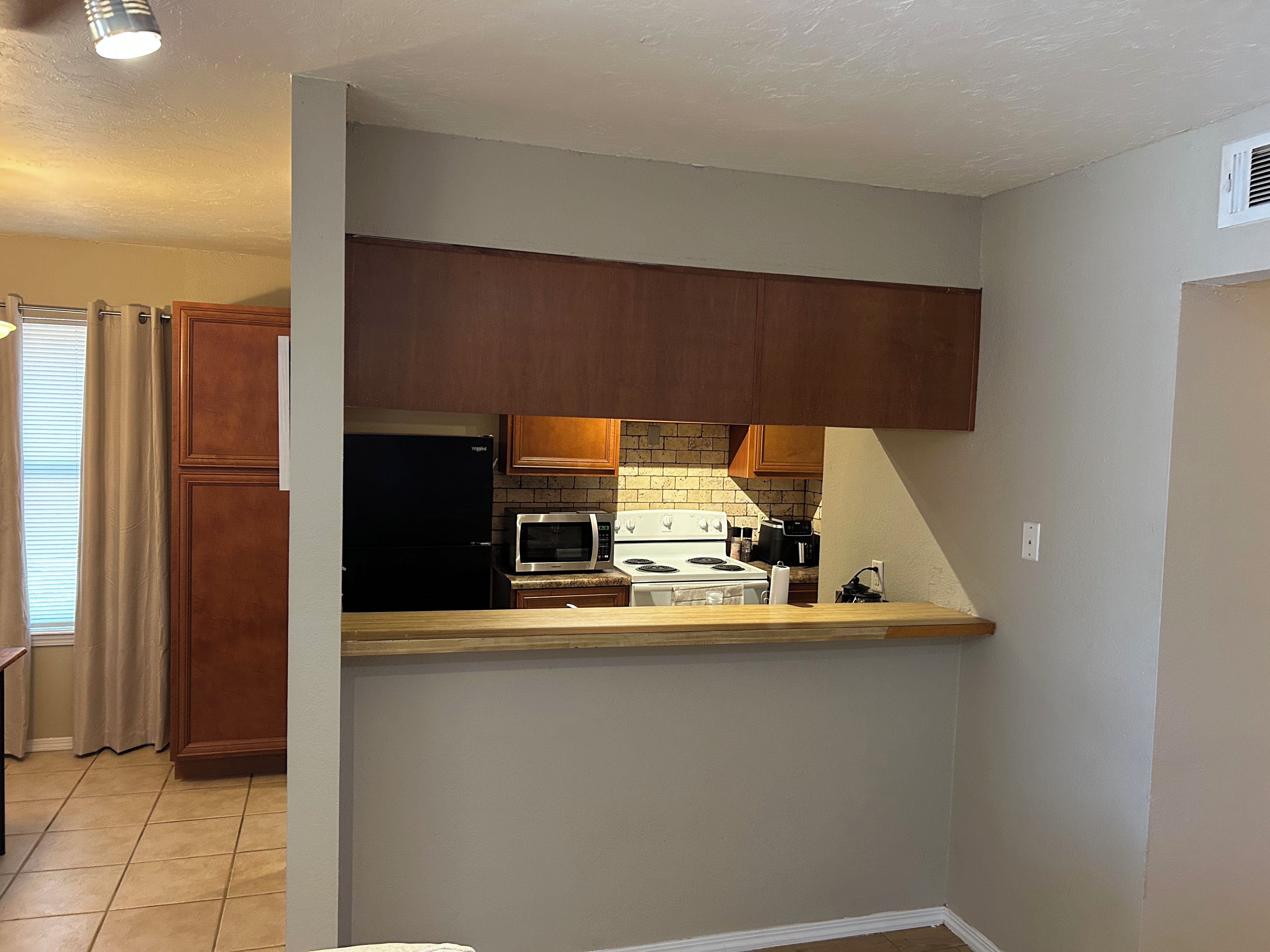Una cocina con armarios de madera, microondas, estufa y refrigerador.