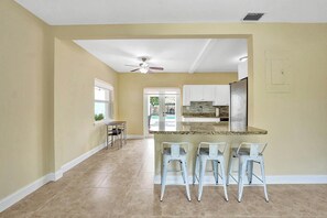A kitchen with a central island, bar stools, and a ceiling fan. - Tropical Oasis in the Heart of Fort Lauderdale • Minutes to the Beach (Fort Lauderdale)