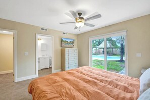 A bedroom with a bed, a ceiling fan, a sliding glass door to a backyard, and a small bathroom. - Tropical Oasis in the Heart of Fort Lauderdale • Minutes to the Beach (Fort Lauderdale)