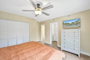 A bedroom with a bed, a ceiling fan, a wardrobe, a dresser, and a television displaying a pool. - Tropical Oasis in the Heart of Fort Lauderdale • Minutes to the Beach (Fort Lauderdale)