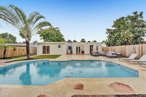 A backyard with a swimming pool, a patio with outdoor furniture, and a wooden fence. - Tropical Oasis in the Heart of Fort Lauderdale • Minutes to the Beach (Fort Lauderdale)
