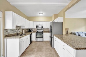A kitchen with white cabinets, granite countertops, stainless steel appliances, and a tiled backsplash. - Tropical Oasis in the Heart of Fort Lauderdale • Minutes to the Beach (Fort Lauderdale)