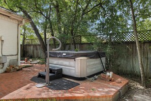A backyard with a hot tub, a brick patio, and a wooden fence. - Aggieland Oasis: Sleeps 12, Pool, Hot Tub, 7 Min to Texas A&M (College Station)