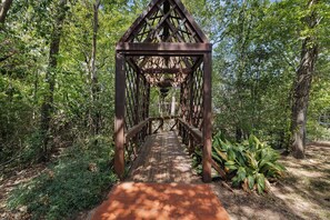 Eine Holzbrücke mit einer dreieckigen Dachkonstruktion, umgeben von dichtem Grün.