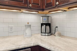 Eine Küche mit Kaffeemaschine, Kaffeekanne und einer Wandsteckdose.