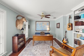 A room with a wooden desk, a globe map, a guitar, and a bookshelf. - Aggieland Oasis: Sleeps 12, Pool, Hot Tub, 7 Min to Texas A&M (College Station)