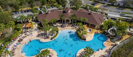 A large outdoor swimming pool surrounded by lounge chairs and palm trees.