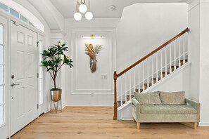 Un couloir avec un escalier, une plante en pot et un élément décoratif fixé au mur.