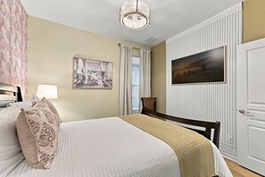 A bedroom with a bed, a nightstand, a lamp, a painting, and a door. - 6BR Near Disney Pool Games and Themed Rooms (Kissimmee)