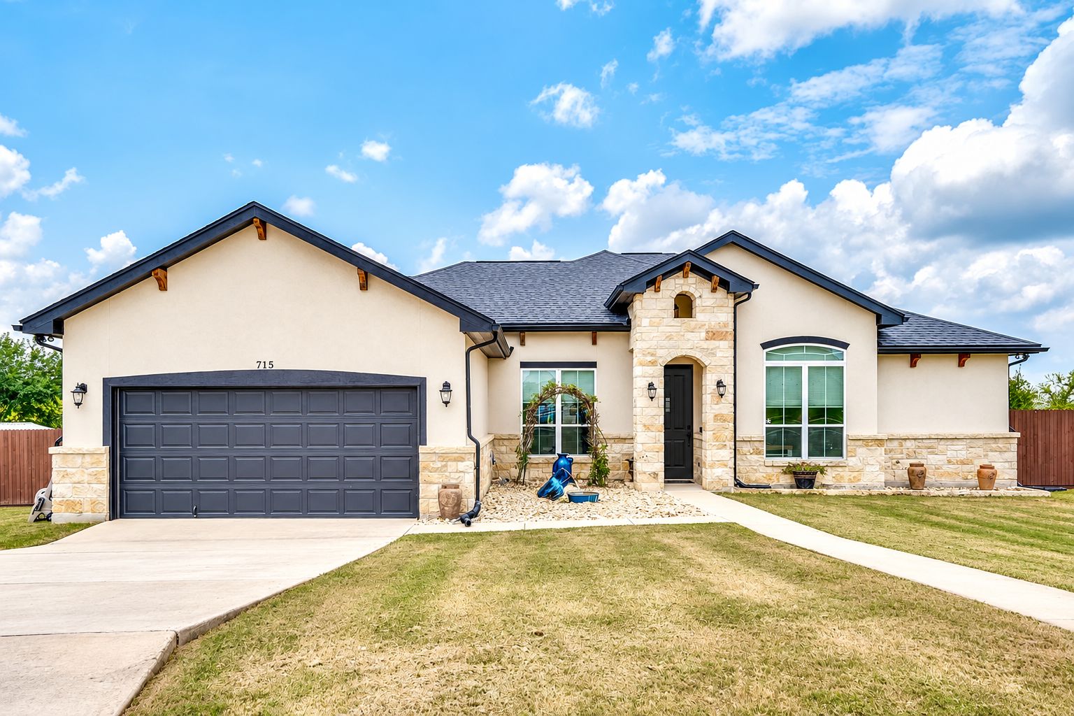 A single-story house with a garage, a stone entrance, and a landscaped front yard.
