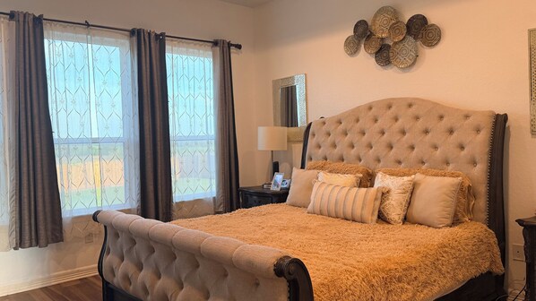 A bedroom with a tufted headboard, a fluffy beige bedspread, and a nightstand with a lamp and a picture frame. - Stay near Randolph AFB! Perfect for military families, TDY & vacationers (Saint Hedwig)
