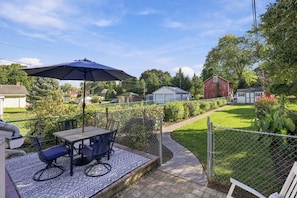 A patio with a table and chairs, a blue umbrella, and a view of a residential area with houses and a fenced yard. - Be our guest at Easy on Main in the heart of Lititz, Pa! (Lititz)