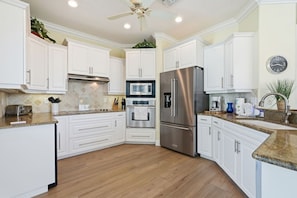 A modern kitchen with white cabinets, stainless steel appliances, and a wooden floor. - Steps to the Beach! 3BR w/Gulf Views! Pool*Jacuzzi (Fort Myers Beach)