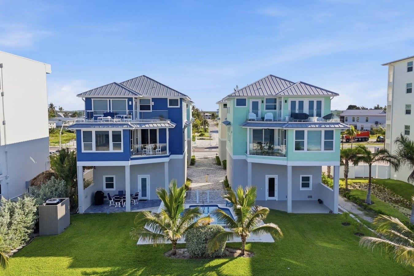 A two-story residential building with a balcony, a small pool, and a well-maintained lawn.