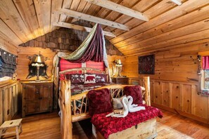A wooden cabin interior with a bed, a nightstand, and a wall-mounted lamp. - Romantic Honeymoon Cabin*Hot Tub*Privacy*Firepit (Sevierville)