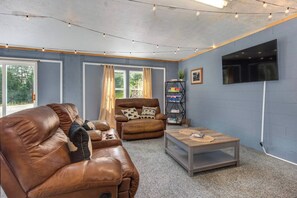 Ein Wohnzimmer mit einem braunen Ledersofa, einem braunen Sessel, einem Couchtisch und einem Bücherregal mit Büchern.