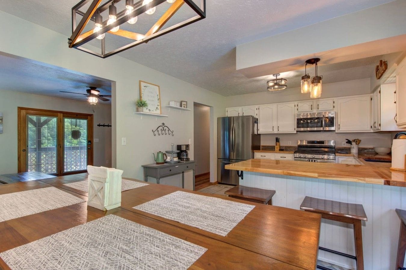 A modern kitchen with stainless steel appliances, a wooden island, and pendant lighting.