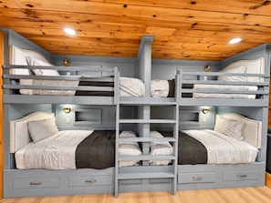 Quarto com beliche, teto de madeira e gavetas embutidas.