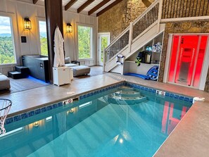 An indoor swimming pool with a stone wall, a staircase, and a view of the outdoors. - 4BR w/Pool*Sauna*Cold Plunge*Views*Games*Fireplace (Sevierville)