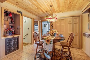 A dining area with a round table, chairs, and a chandelier. There is a door leading to another room and a wall with a decorative panel. - Honeymoon Cabin w/MTN Views*Hot Tub*Games*Peaceful (Sevierville)