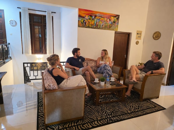 Un grupo de personas sentadas en una sala de estar moderna con un alfombra de estampado de cebra, un cuadro en la pared y un reloj.